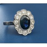 An oval sapphire & diamond millegrain set cluster ring, the sapphire weighing approximately 2.75