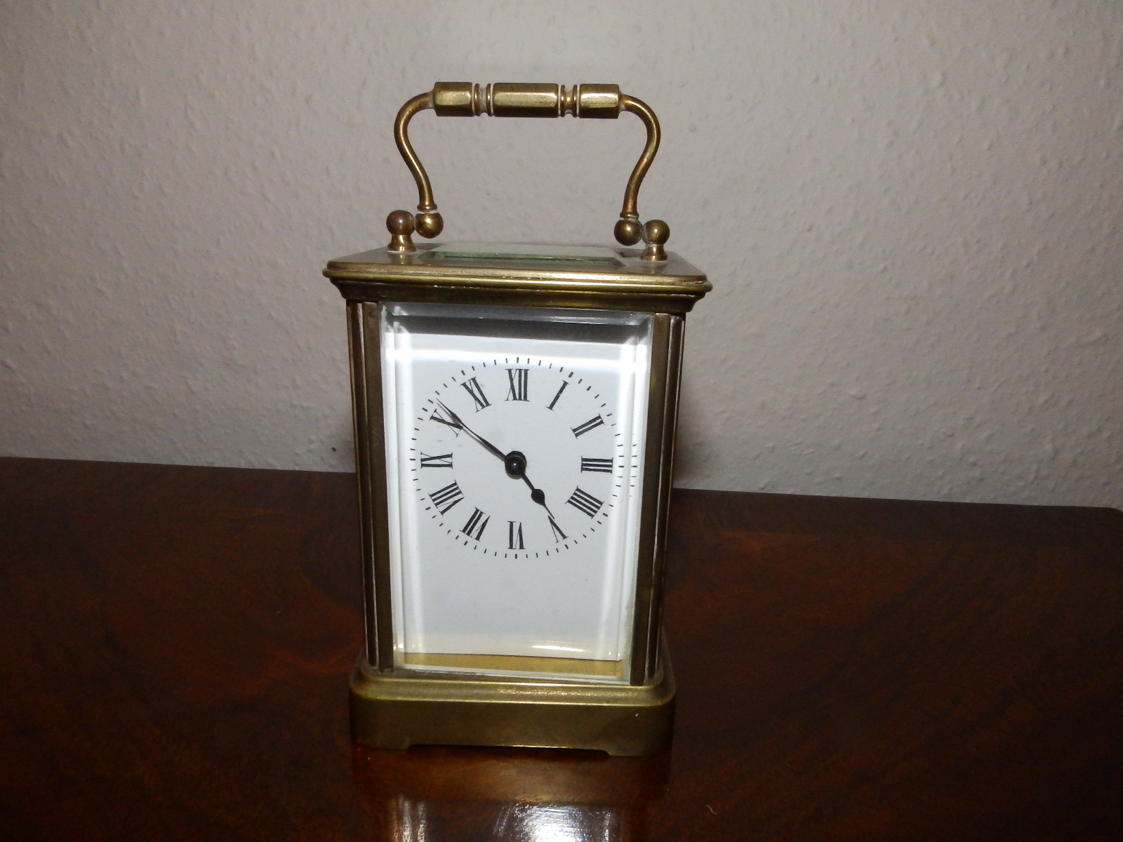 A brass carriage clock with white enamel dial, 4.5" excluding handle.