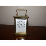 A brass carriage clock with white enamel dial, 4.5" excluding handle.