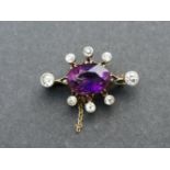 A late 19th/early 20thC amethyst & diamond set gold brooch, the central oval cut amethyst surrounded