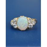 An opal & diamond set 18ct gold ring, the oval claw set opal flanked by six old cut diamonds. Finger