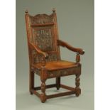 An oak Wainscot chair, with carved back, downswept arms with fluted supports and with solid seat,