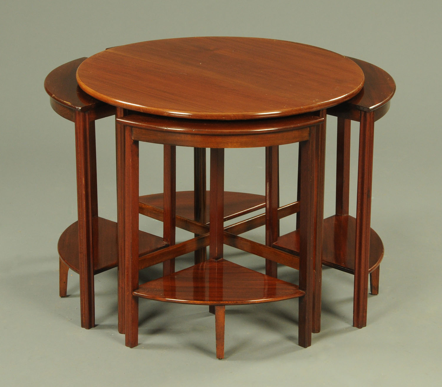 An Edwardian mahogany circular nest of tables, with one large table and four quadrant tables.