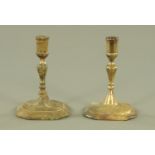 Two antique brass candlesticks, with faceted columns and stepped bases. Height 15 cm.