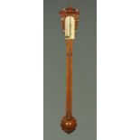 A Victorian oak stick barometer, with exposed tube and carved head and foot.