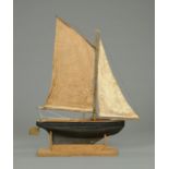 An early 20th century pond yacht, wooden painted hull, simulated planked deck, single mast.