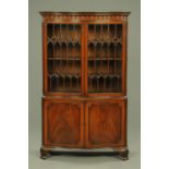 A serpentine mahogany glazed bookcase on cupboard, 20th century,