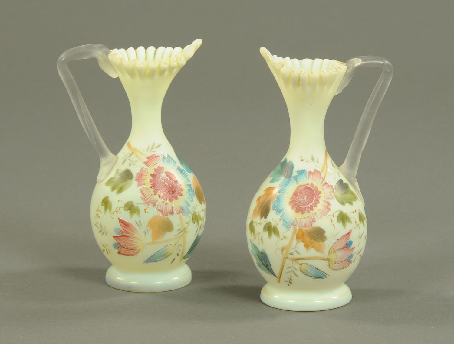 A pair of Victorian opaque glass vases, with folded rims and hand painted with floral sprays.