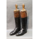 A pair of early 20th century riding boots with wooden shoe trees, black and tan approximate size 8.