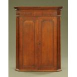 A George III oak hanging corner cupboard, with bats wing inlaid circular medallions.