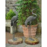 Two bronze heron ornaments, each raised on tree section base. Height 132 cm.
