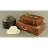 A vintage tin hat box containing a pith helmet, and two leather suitcases.