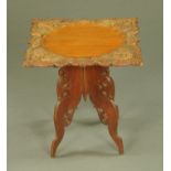 An Eastern carved wooden square topped occasional table, with folding stand. Width 56 cm.
