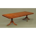 A George III style mahogany crossbanded twin pillar dining table with two leaves,