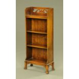 An oak open bookcase, with fretwork pediment and with four shelves,