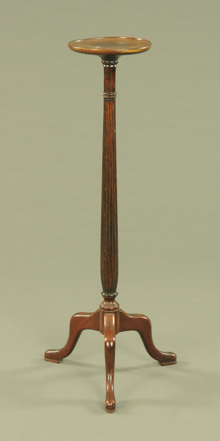 A mahogany torchere, with reeded column and three downswept legs terminating in pad feet.