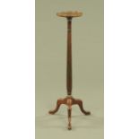 A mahogany torchere, with reeded column and three downswept legs terminating in pad feet.