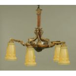 A metal and wood five branch light fitting, with dolphin supports and with yellow glass shades.