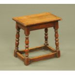 An oak joint stool, rectangular with moulded edge and raised on splayed turned legs with stretchers.
