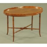 A 19th century mahogany oval tray with wavy gallery, supported on a later stand,