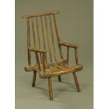 An antique Windsor style spindle backed armchair, with slatted seat and raised on angled legs.