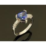 An 18 ct white gold ring, set with a trilliant cut Tanzanite and diamond set shoulders,