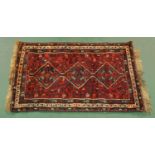An Eastern fringed rug, with three diamond shaped centre panels and multiple line border,