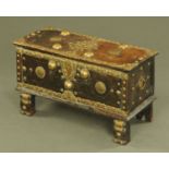 An Indian hardwood casket, brass embossed and raised on short legs. Width 81.