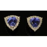 A pair of 18 ct white gold earrings, set with trilliant cut Tanzanites within a diamond cluster,