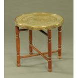 An Indian Benares brass topped occasional table with folding stand. Diameter 60 cm.