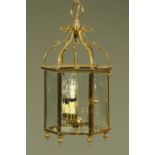 A brass hanging lantern light fitting, with three bulbs, glass panels and door.