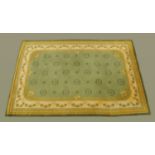 A woollen rug, principal colours green, yellow and beige,