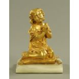 A gilt bronze figure of a child kneeling on a cushion, raised on an onyx base.