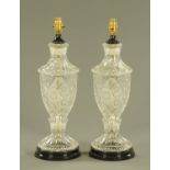 A pair of clear glass vase form table lamps, etched and moulded and raised on a circular base.