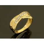 A ladies 18 ct gold crossover ring set with seven diamonds, ring size L, +/- .