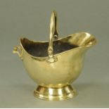 A Victorian brass helmet shaped coal scuttle, supported upon a circular foot,
