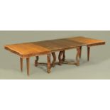 A walnut extending dining table with four leaves, of slightly shaped outline,