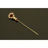A gold coloured metal stick pin set with garnets and seed pearls, cased. Length 75 mm.