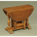 A reproduction oak low drop leaf gate leg table, with turned columns and sledge supports.