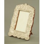 An Assyrian silver coloured metal frame, and later mahogany easel back housing a mirror,