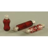 Three Victorian cranberry glass scent bottles, double ended, faceted, faceted and cut and standing,