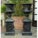 A pair of black painted cast iron garden urns on stands,
