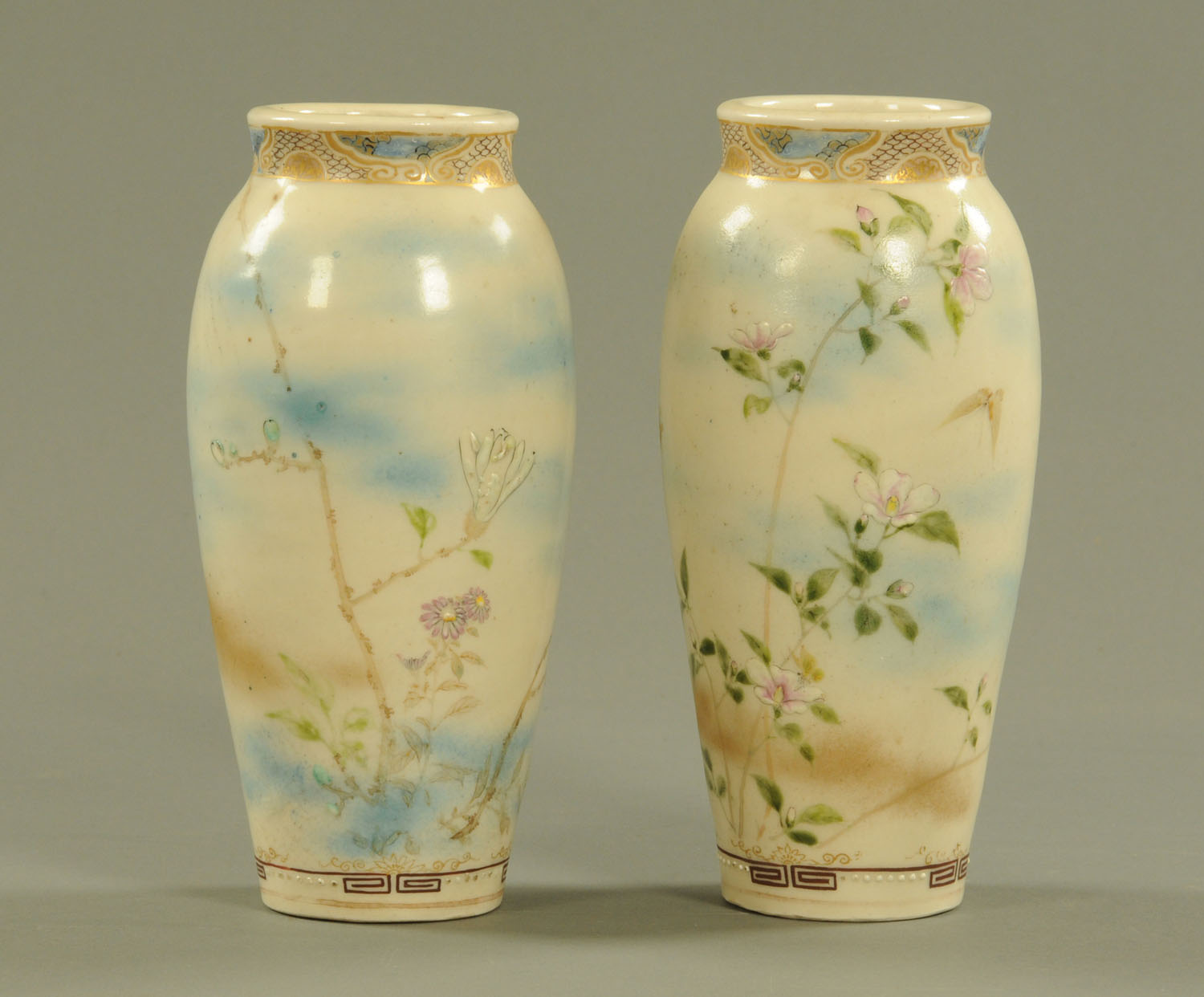 A pair of Japanese Satsuma vases, decorated with butterflies and branches with flowers.