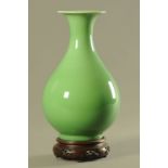 A Chinese porcelain vase, green glaze raised on a wooden stand. Overall height 39 cm.