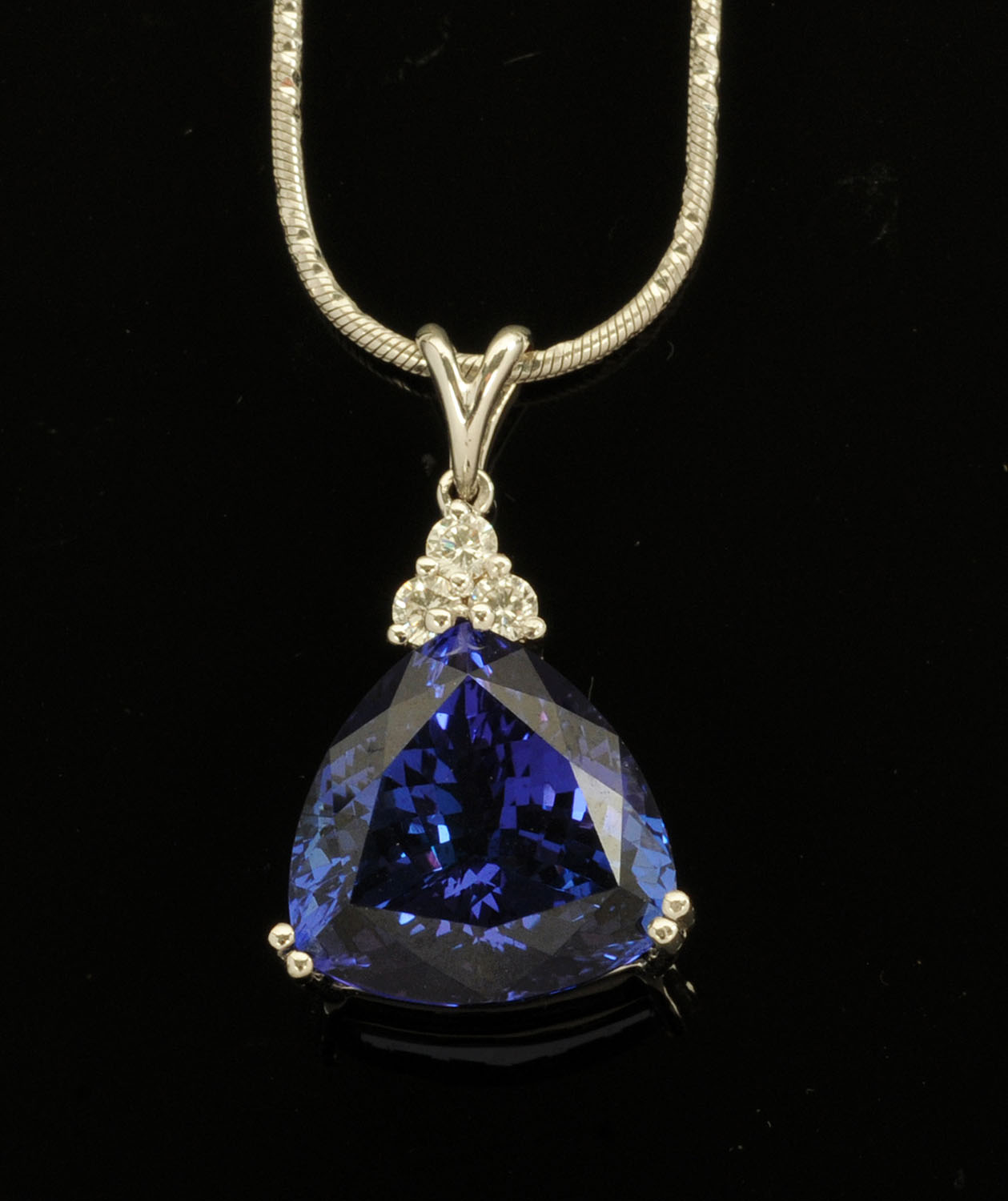 An 18 ct white gold pendant on chain, set with a trilliant cut Tanzanite with diamonds to the bale,