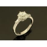 An 18 ct white gold ring, set with a diamond to the centre and with baguette shoulders.