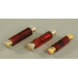 Three Victorian cranberry glass faceted double ended scent bottles, one with jewelled mounts,