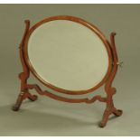 An Edwardian mahogany oval framed toilet mirror, with bevelled glass and shaped supports.