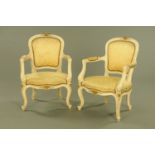 A pair of open armchairs, cream painted with gold coloured upholstery and raised on cabriole legs.
