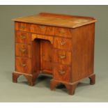 An antique walnut kneehole desk, with rear upstand,